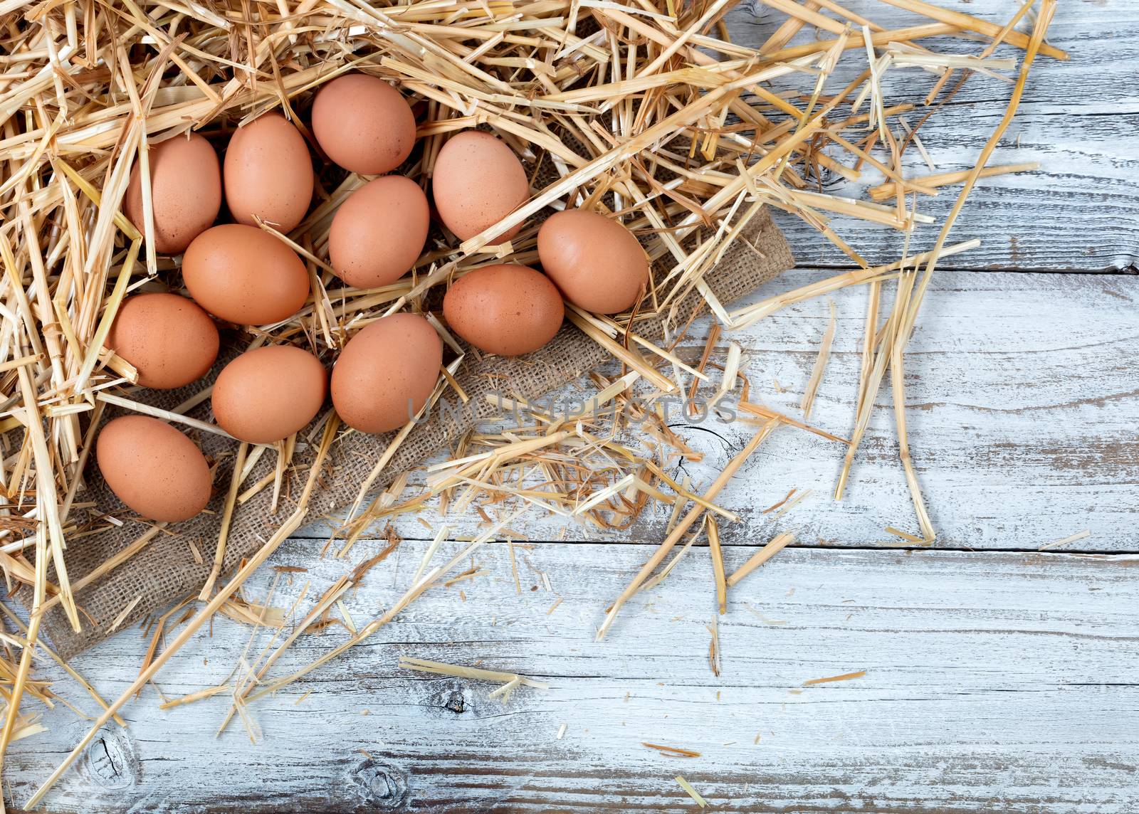 Brown organic raw chicken eggs lying on straw and wooden backgro by tab1962