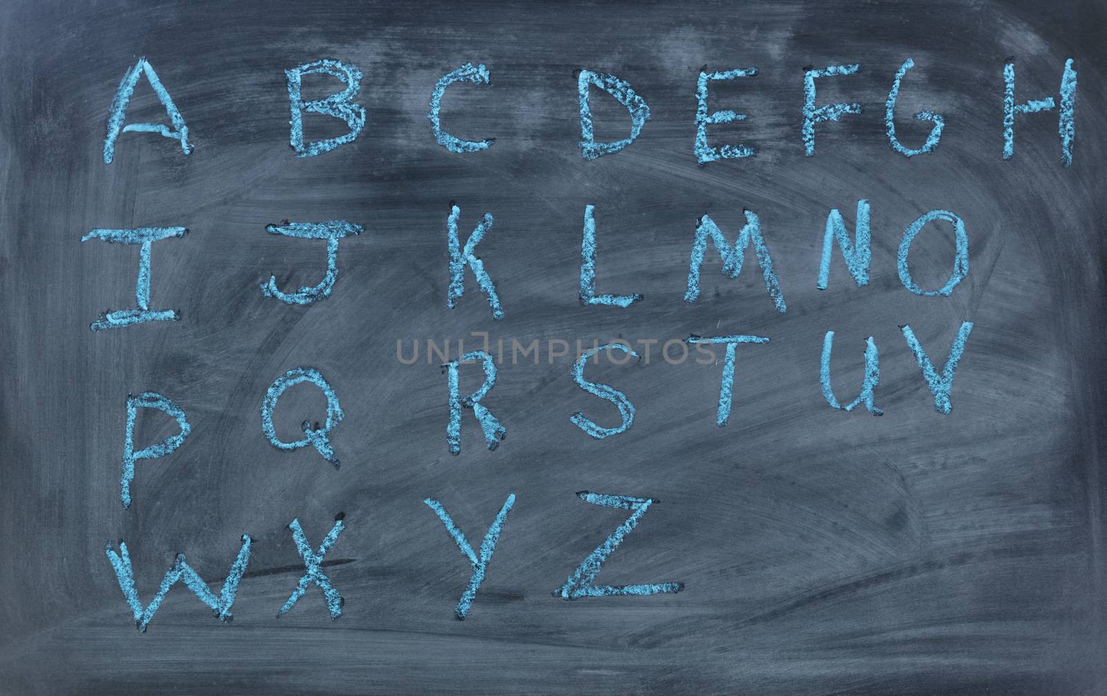 Alphabet letters written with blue chalk on clean blackboard