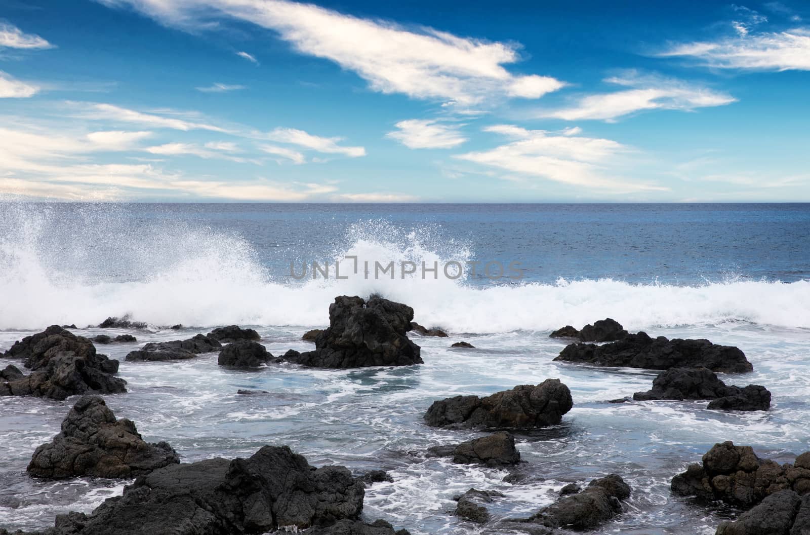 Ocean and rocks with cloudy blue sky 