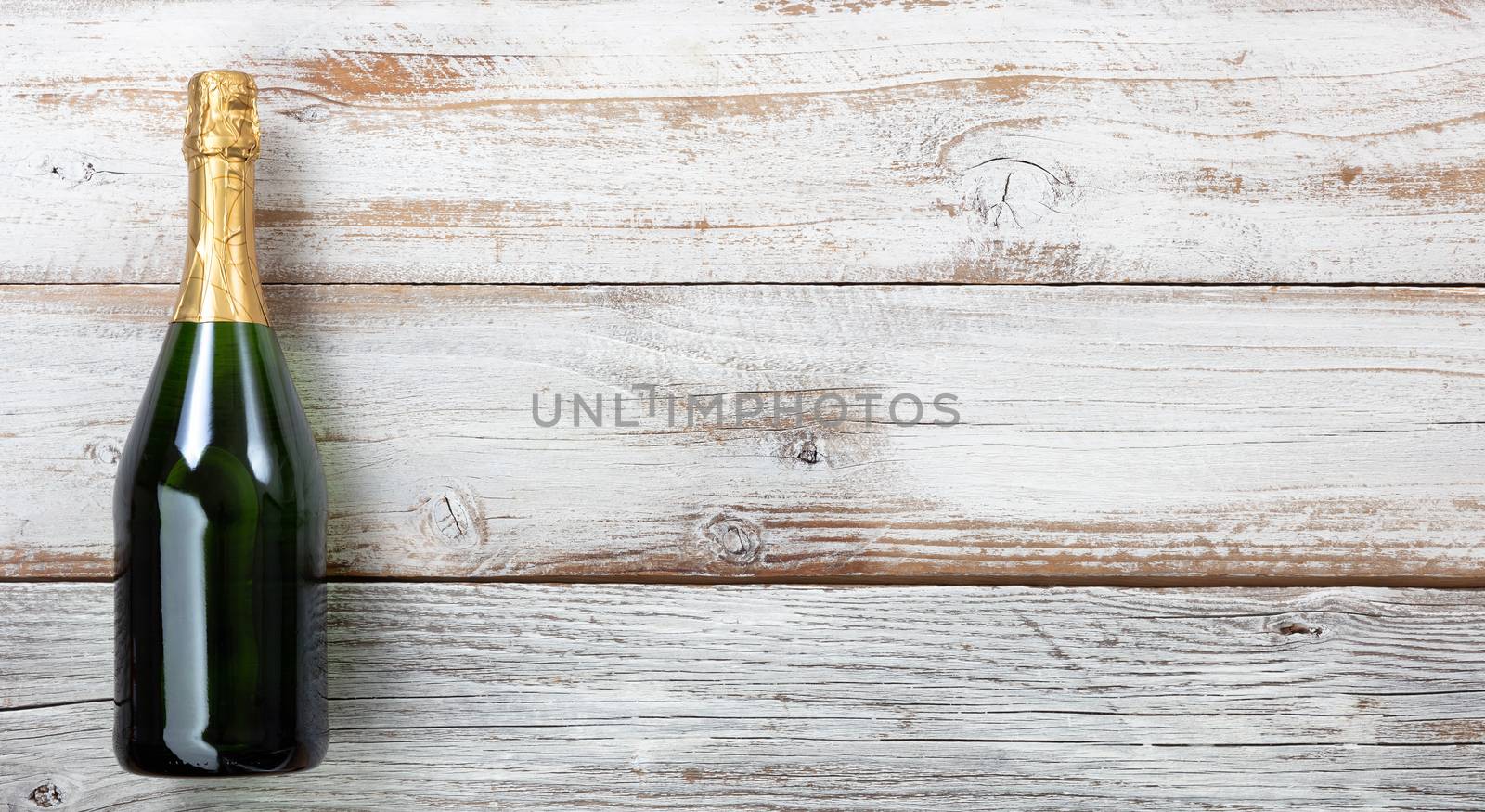 Anniversary background with a bottle of champagne on white rustic wood  