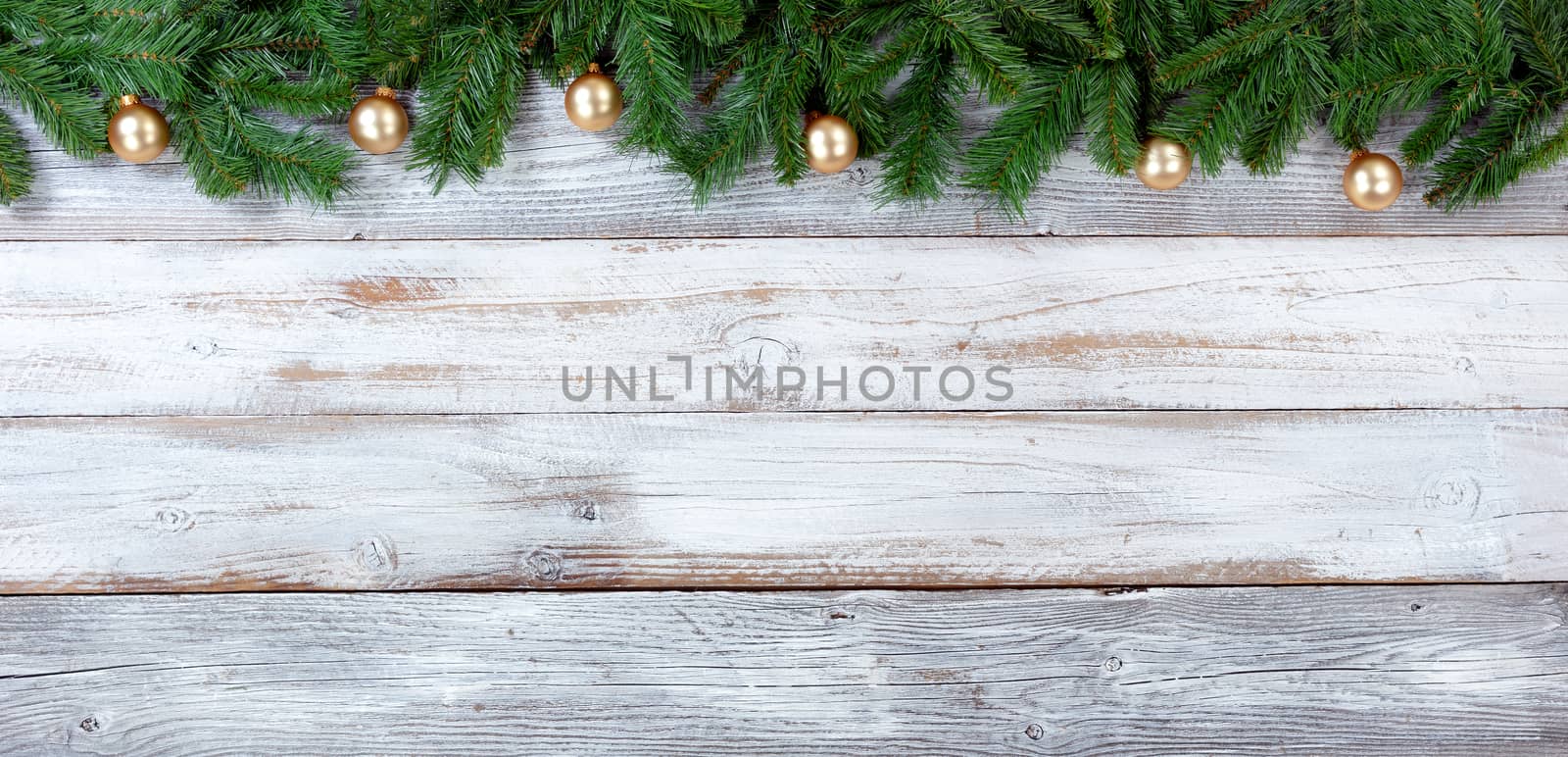 Top border of Christmas evergreen branches and Golden ornaments on white vintage wood