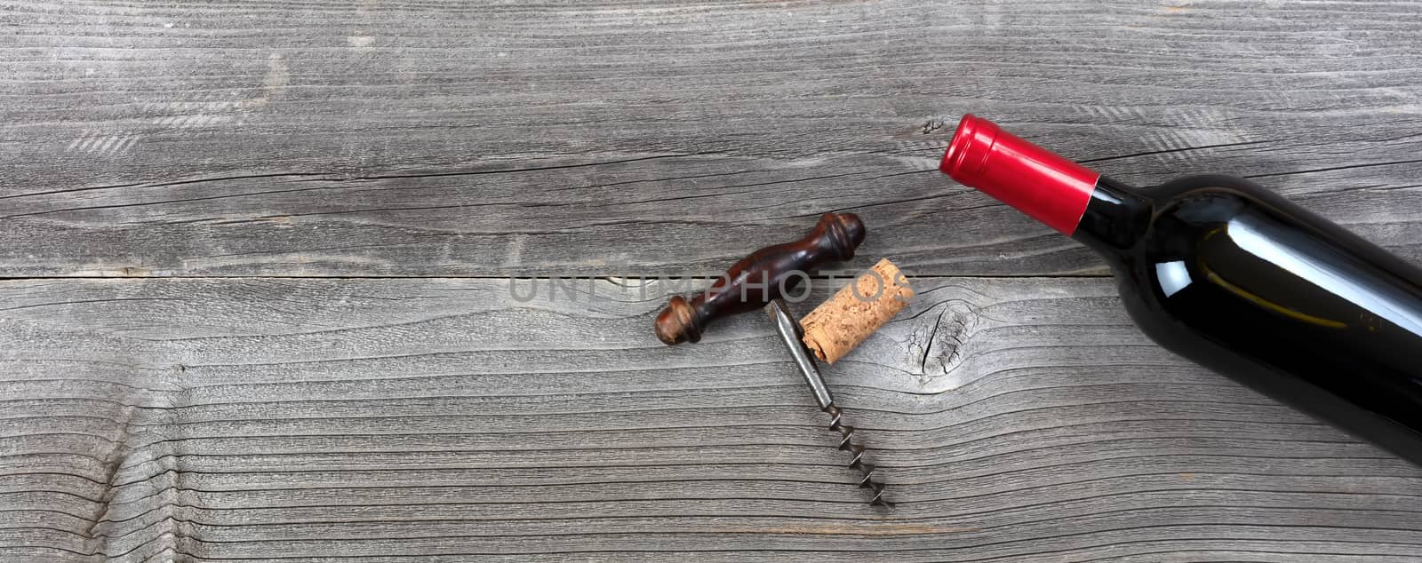 Dark bottle of red wine with vintage corkscrew on rustic wooden  by tab1962