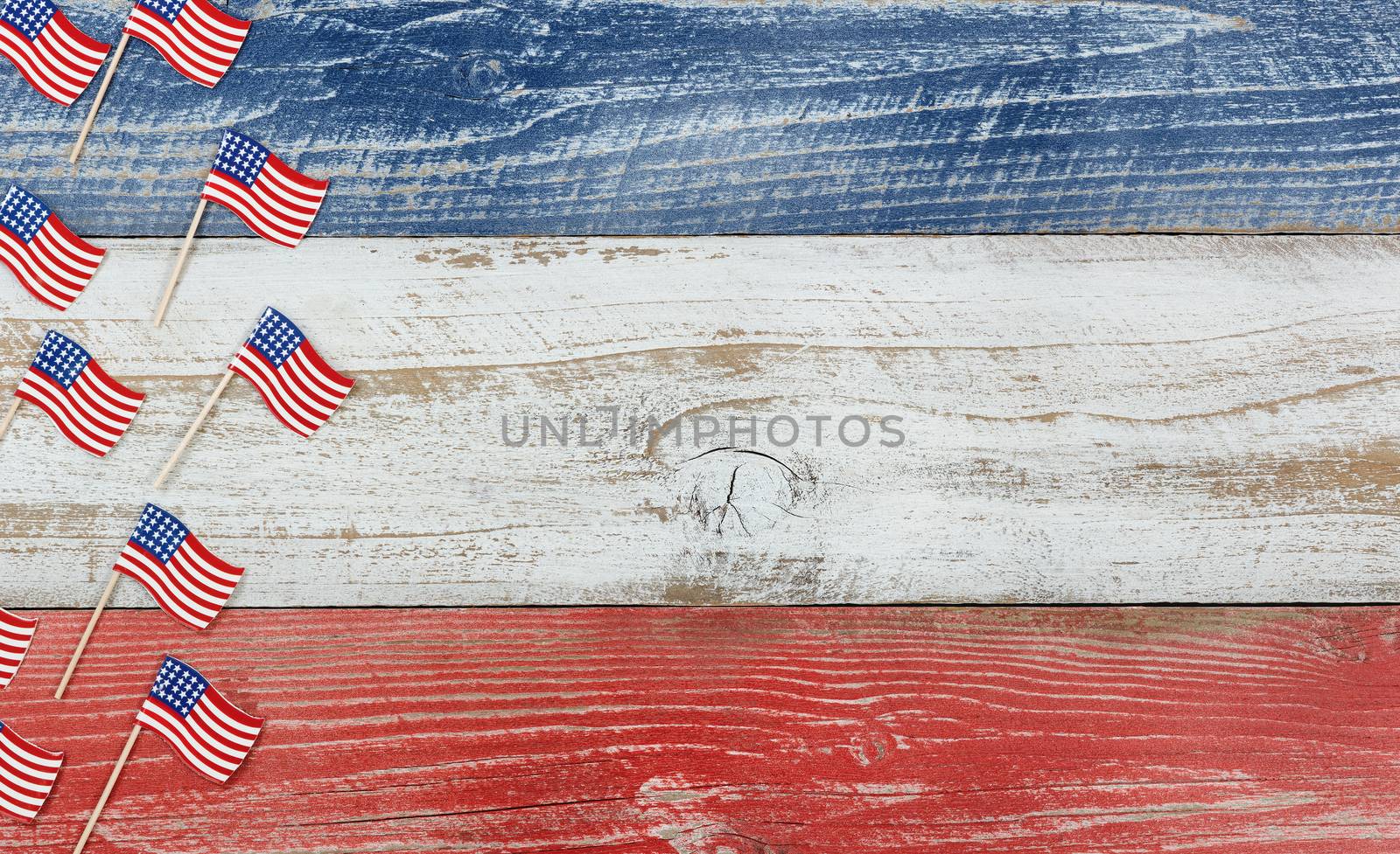 Flay lay view of USA mini flags on rustic wooden boards painted in red, white and blues colors. 