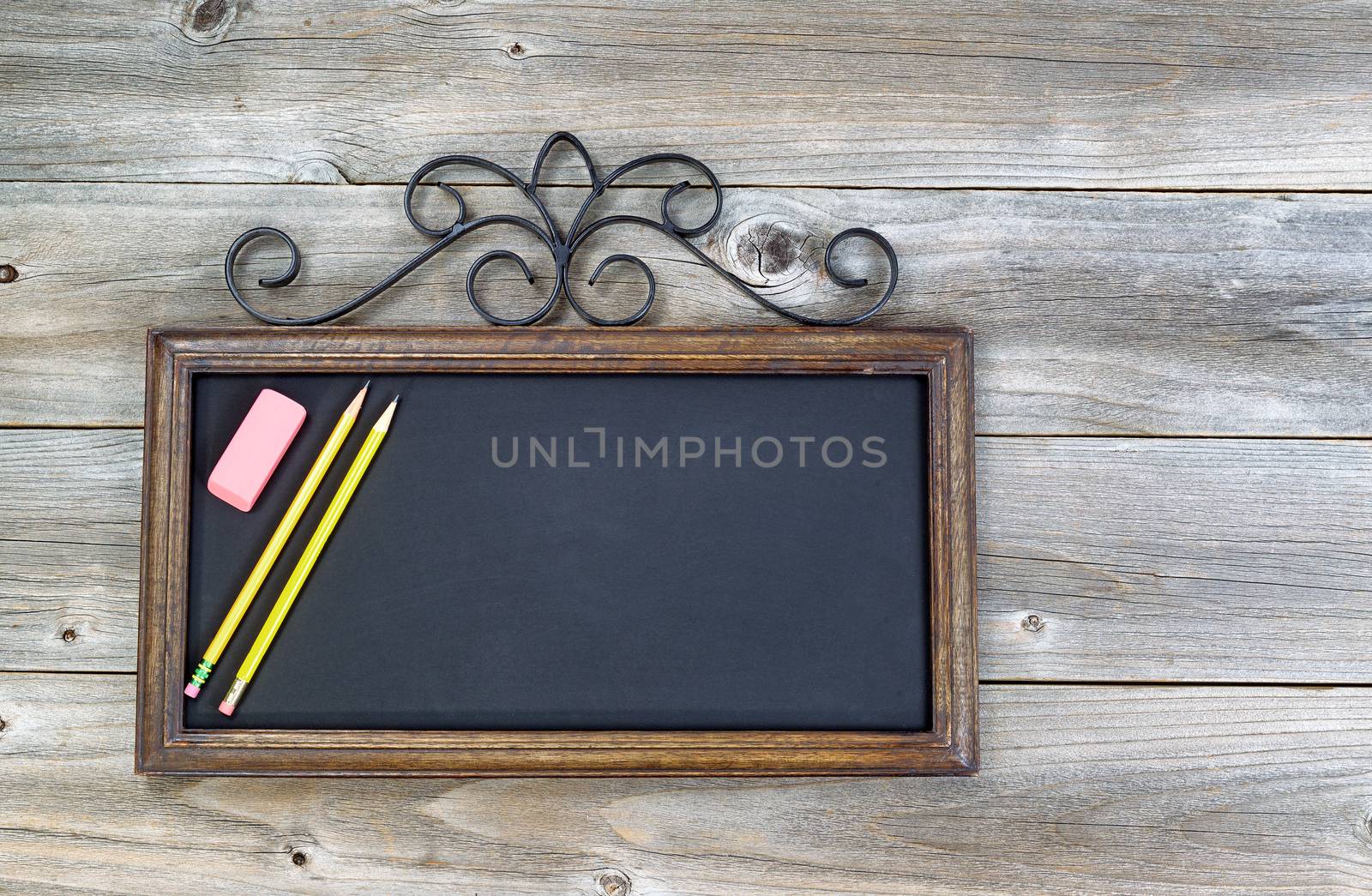 Old fashion chalkboard, pencils and eraser on rustic wood. Layout in horizontal format.