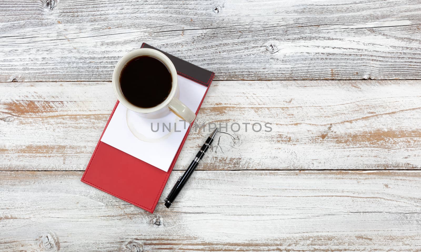 Top view of desktop with red paper notepad, pen and coffee to include stain 