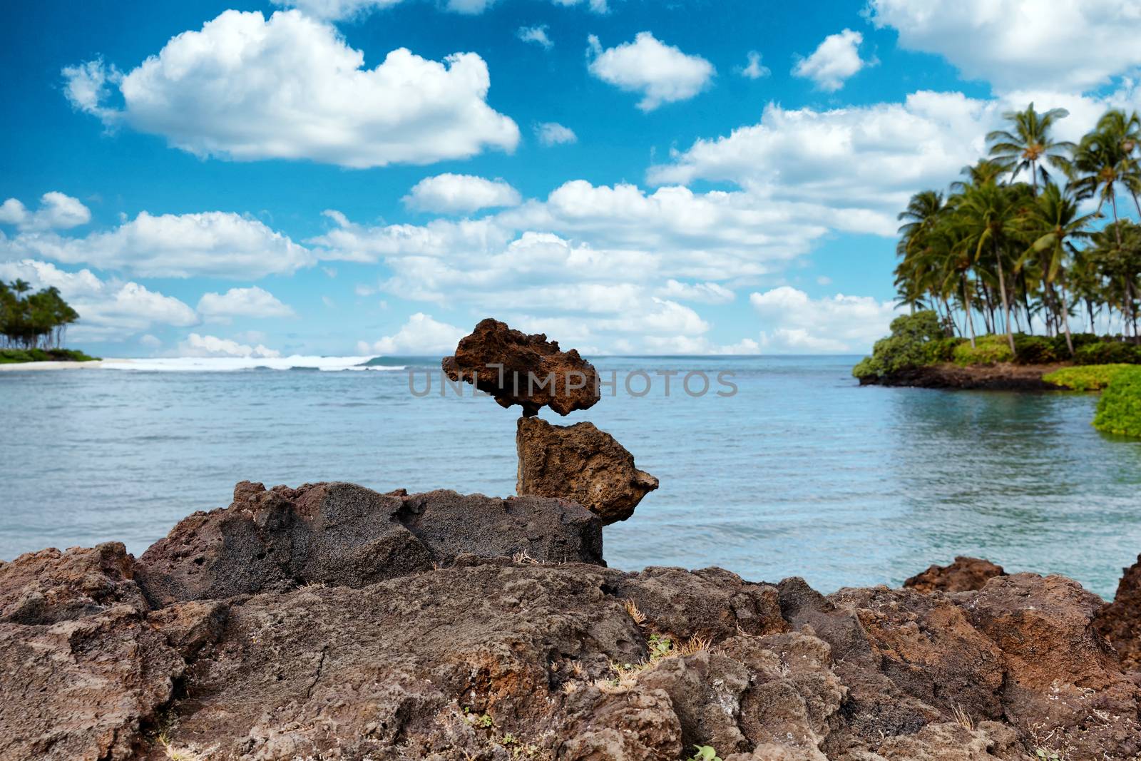 Rocks stacked vertically with ocean waves in background by tab1962