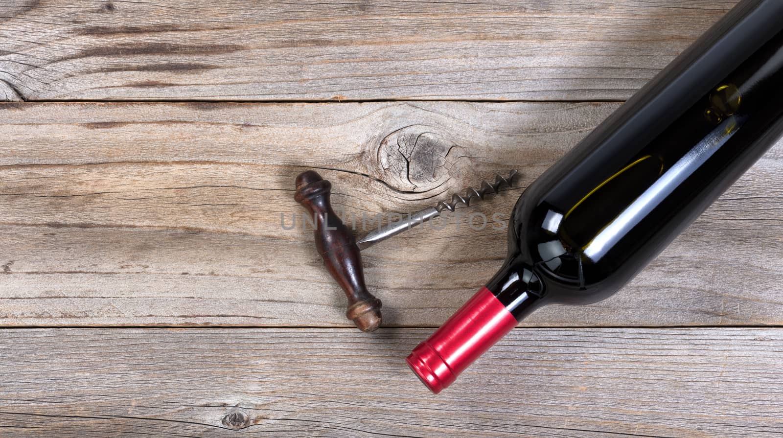 Unopen bottle of red wine with vintage corkscrew on rustic woode by tab1962