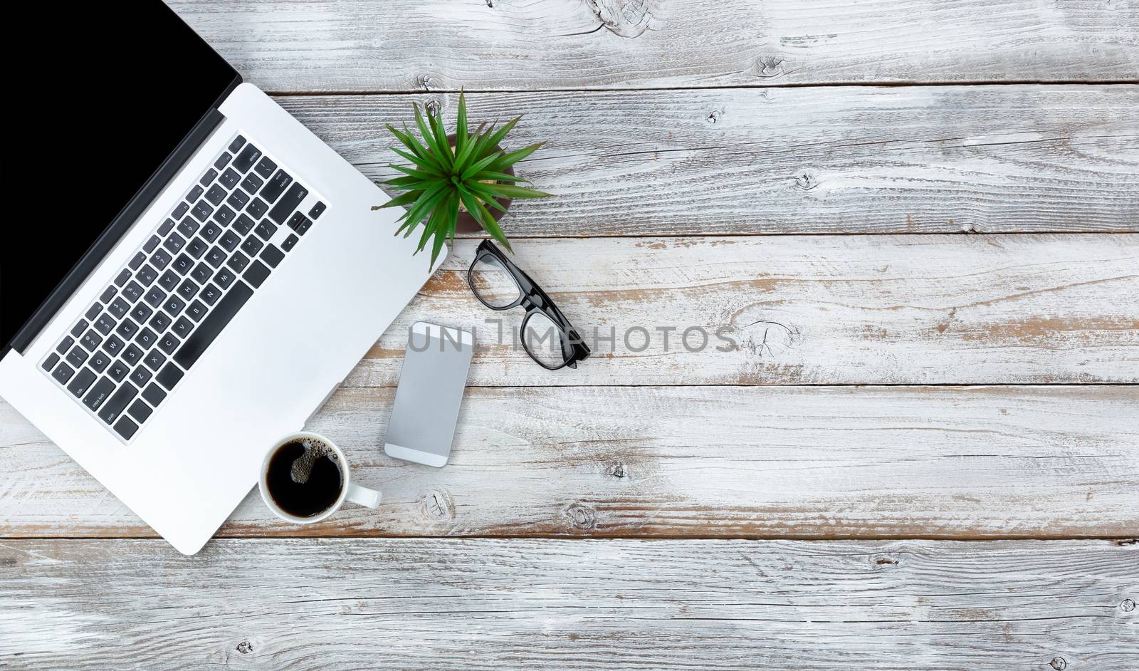 Overhead view of working desktop and smart phone, coffee, reading glasses and baby plant with plenty of copy space 