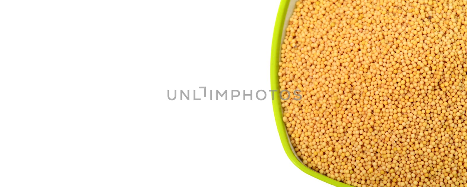 yellow mustard seeds in green bowl isolated on white background