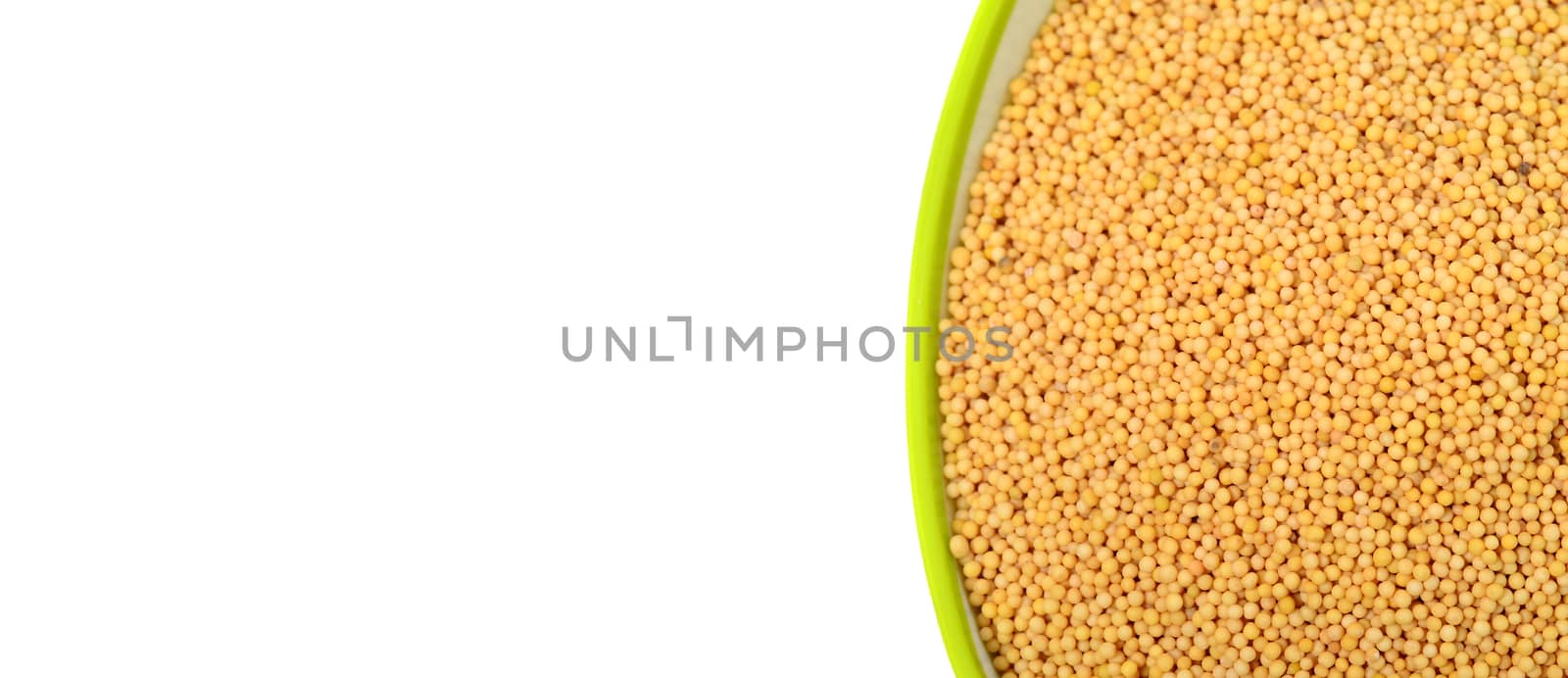 yellow mustard seeds in green bowl isolated on white background