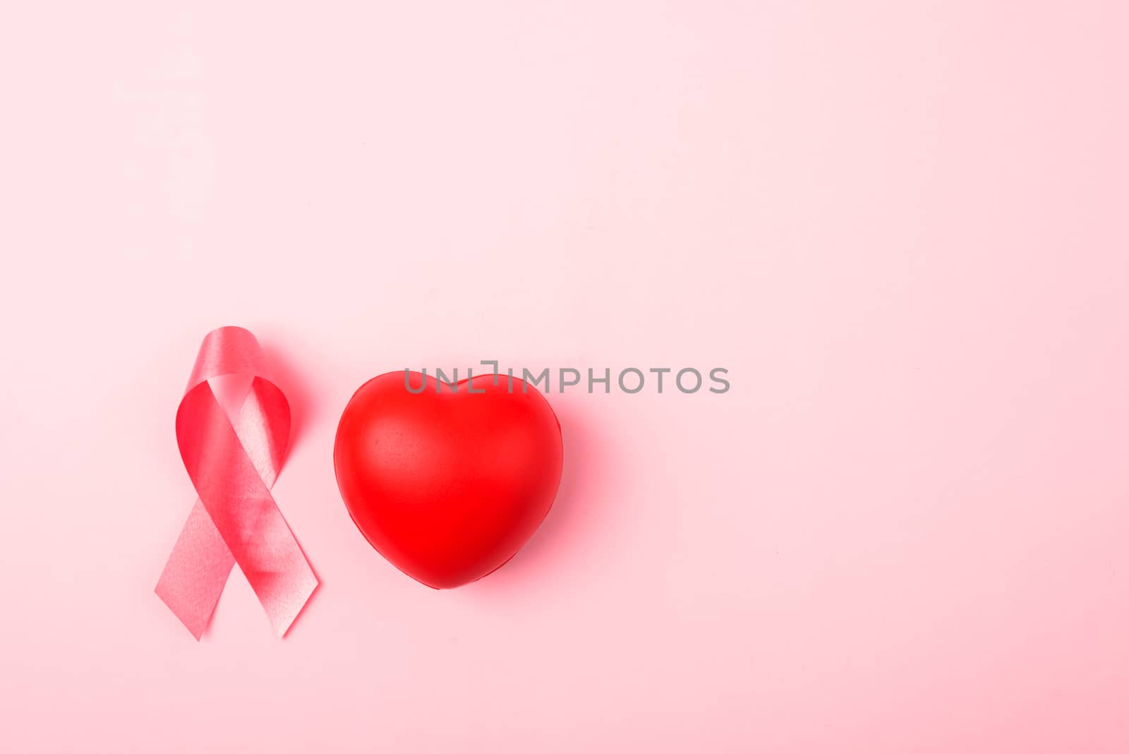 Breast cancer month health concept, flat lay top view, put pink ribbon and Red Heart on pink background with copy space for your text