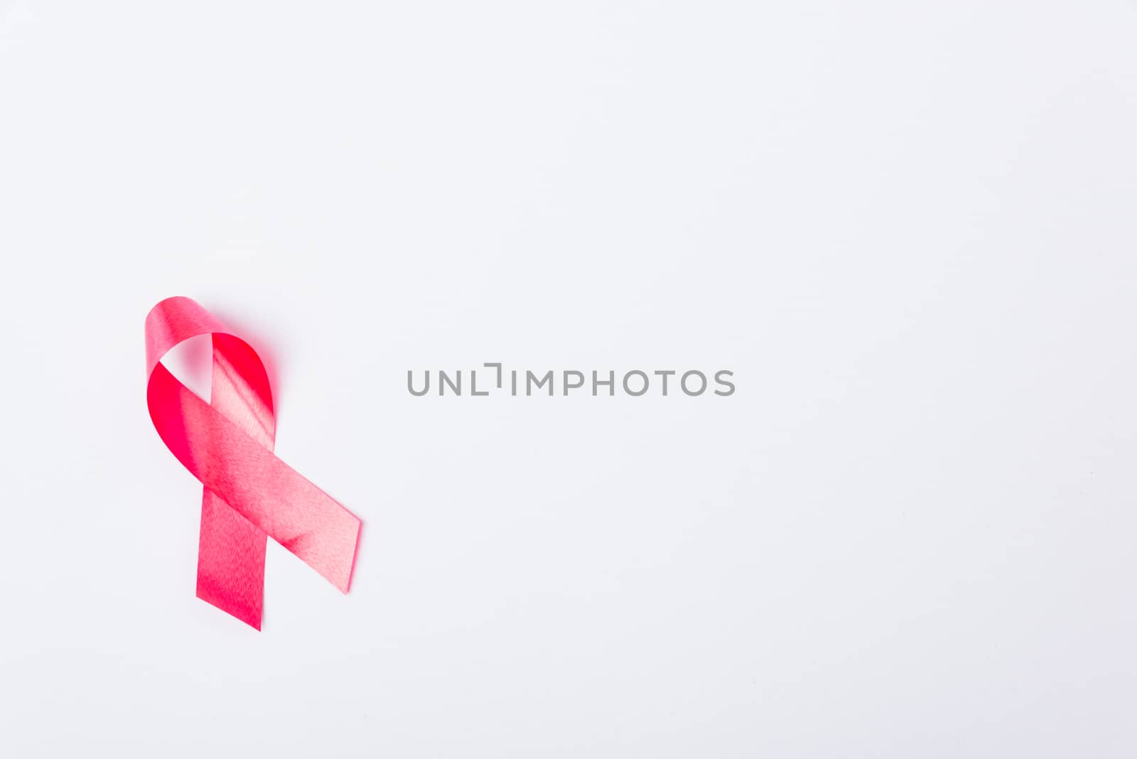 Breast cancer month concept, flat lay top view, pink ribbon on white background with copy space for your text