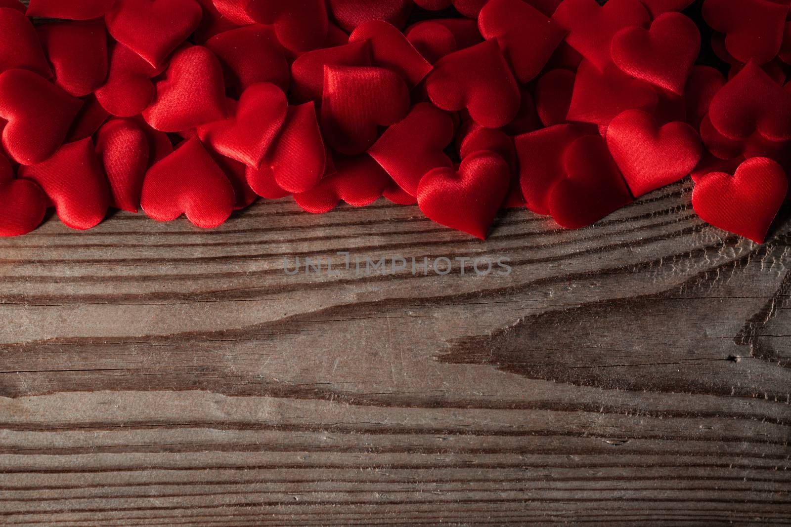 Valentine's day many red silk hearts on wooden background, love concept