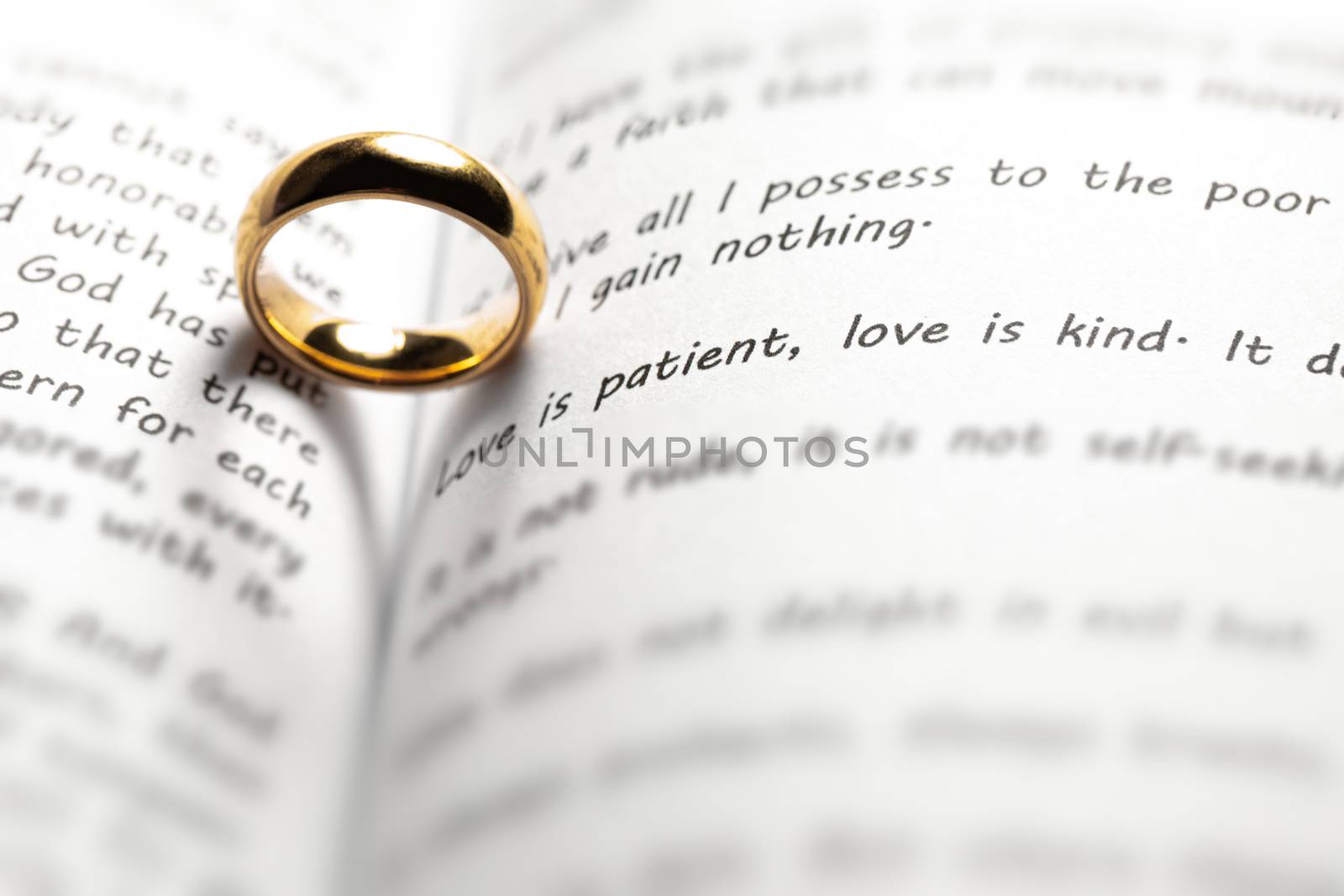 One golden wedding ring on Holy bible book with heart shaped shadow close up