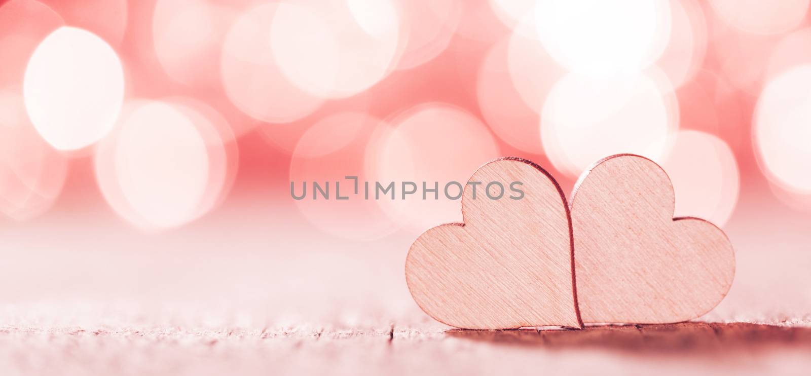Two handmade wooden hearts on beautiful pink bokeh background. Vintage style. Love Valentine's Day concept.