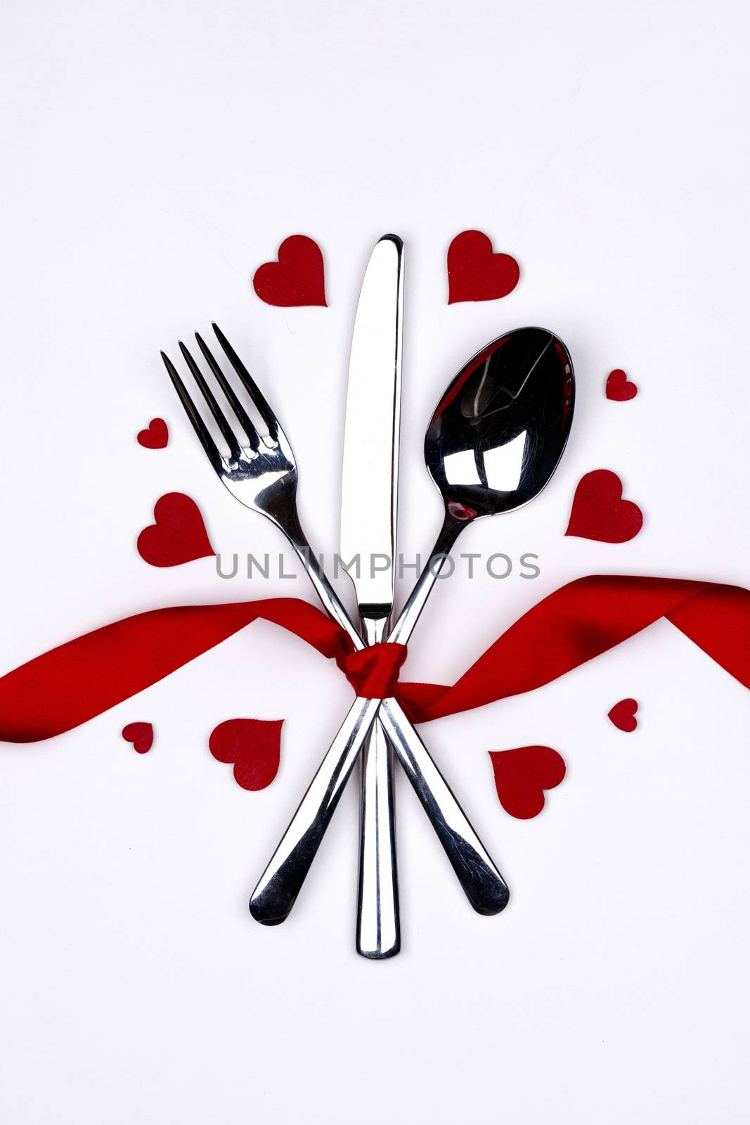 Cutlery set tied with silk ribbon and hearts on white background Valentine day dinner concept