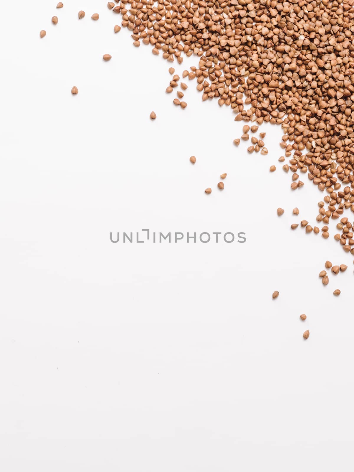 Buckwheat with copy space. Brown raw buckwheat grain on white background. Top view or flat lay. Copy space. Healthy food and diet concept. Buckwheat background. Vertical