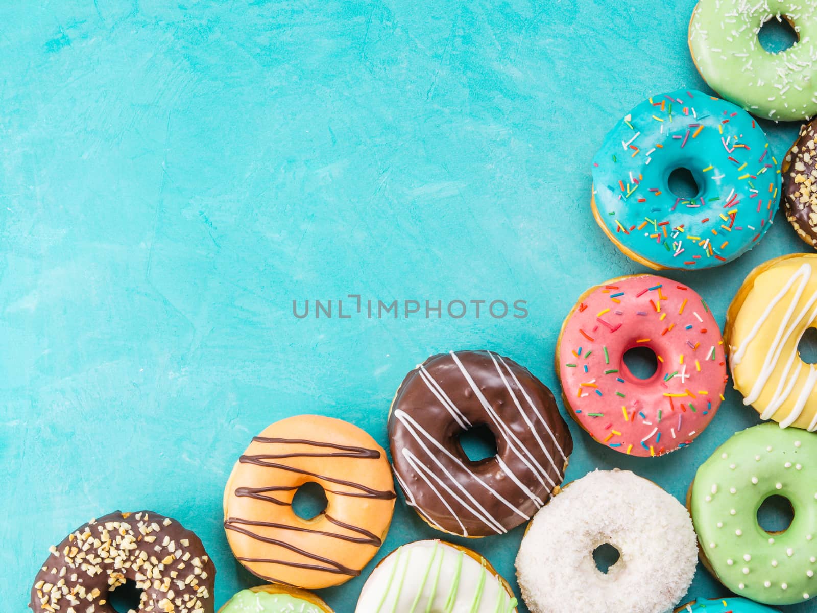 Top view of assorted donuts on blue concrete background with copy space. Colorful donuts background. Various glazed doughnuts with sprinkles.