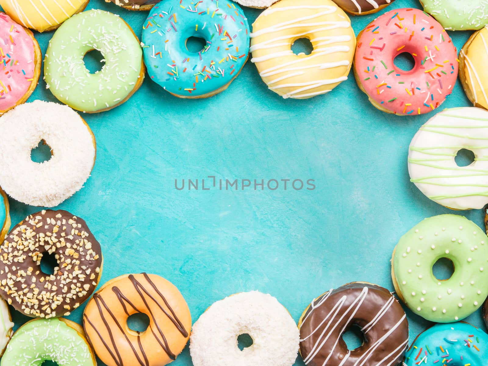 Top view of assorted donuts on blue concrete background with copy space. Colorful donuts background. Various glazed doughnuts with sprinkles.