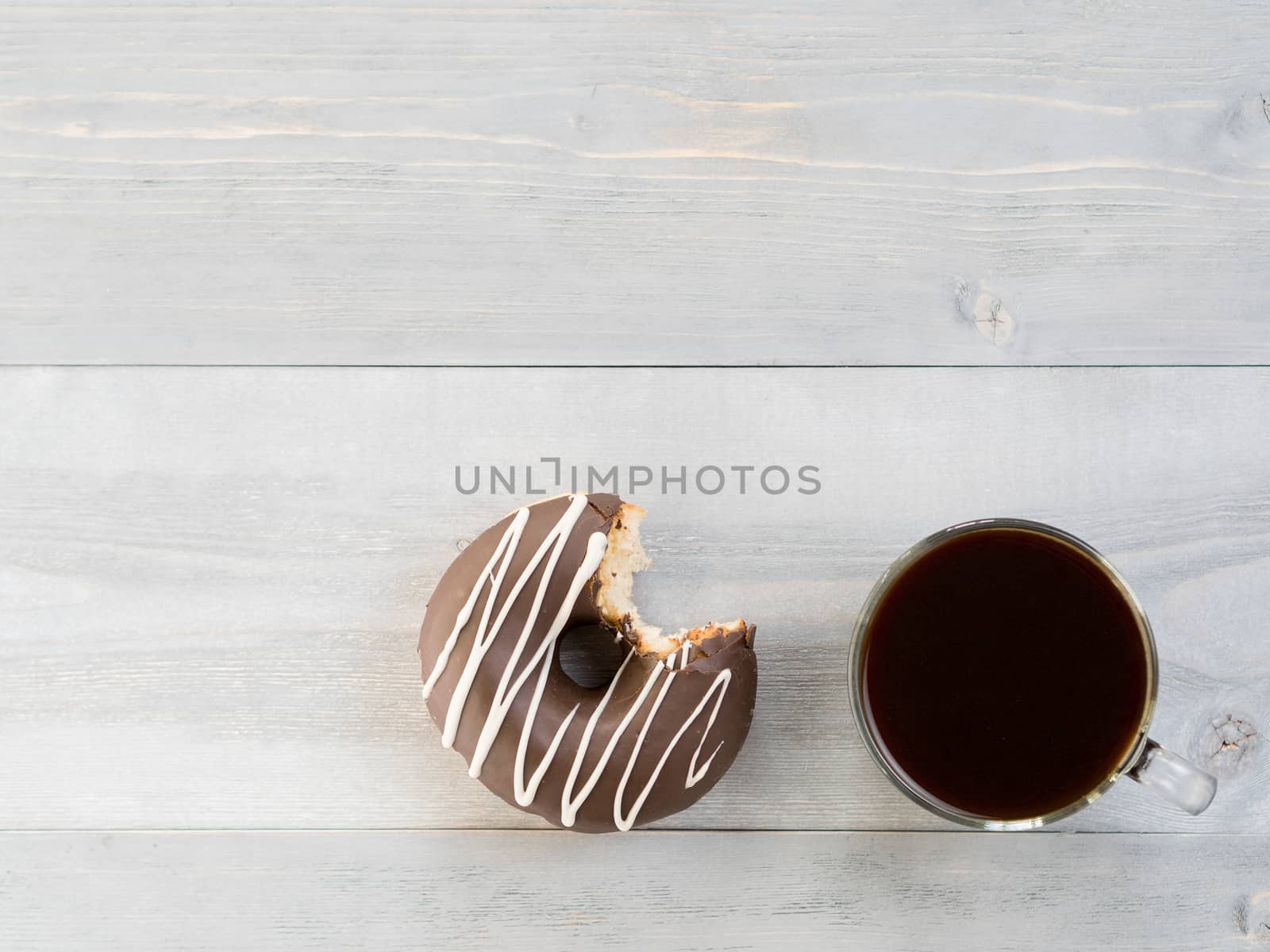 Top view of chocolate donut and coffee on gray wooden background with copy space. Glazed doughnuts and coffee on grey wooden table with copyspace.