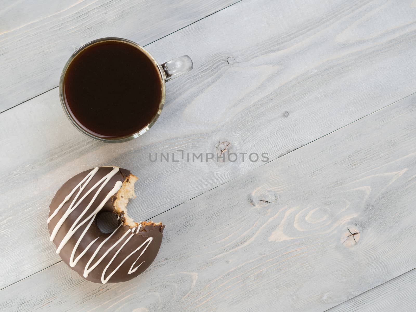 Top view of chocolate donut and coffee on gray wooden background with copy space. Glazed doughnuts and coffee on grey wooden table with copyspace.