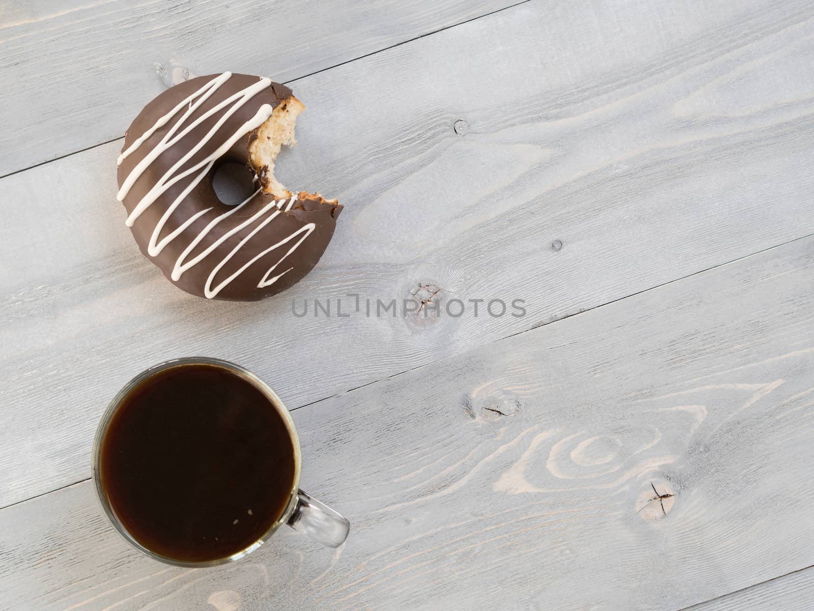 Top view of chocolate donut and coffee on gray wooden background with copy space. Glazed doughnuts and coffee on grey wooden table with copyspace.