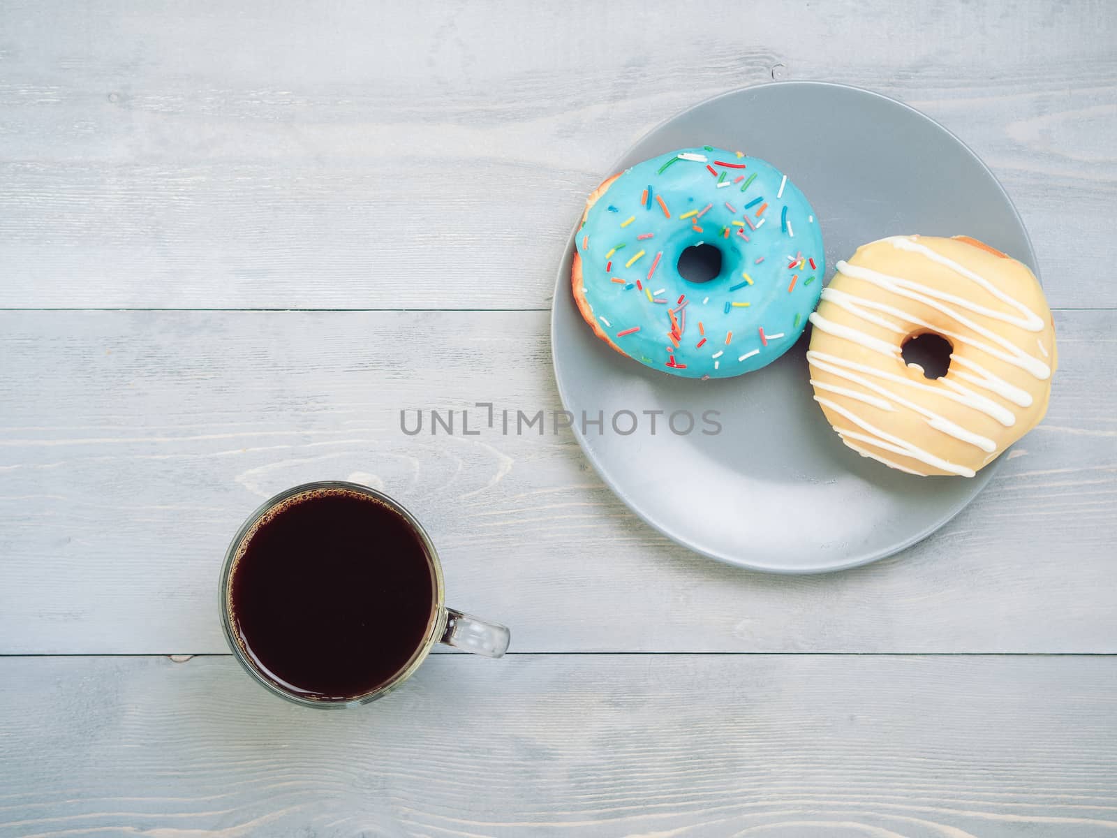 Top view of assorted donuts and coffee on gray wooden background with copy space. Various glazed doughnuts with sprinkles on grey wooden table. Smile sign, good morning concept