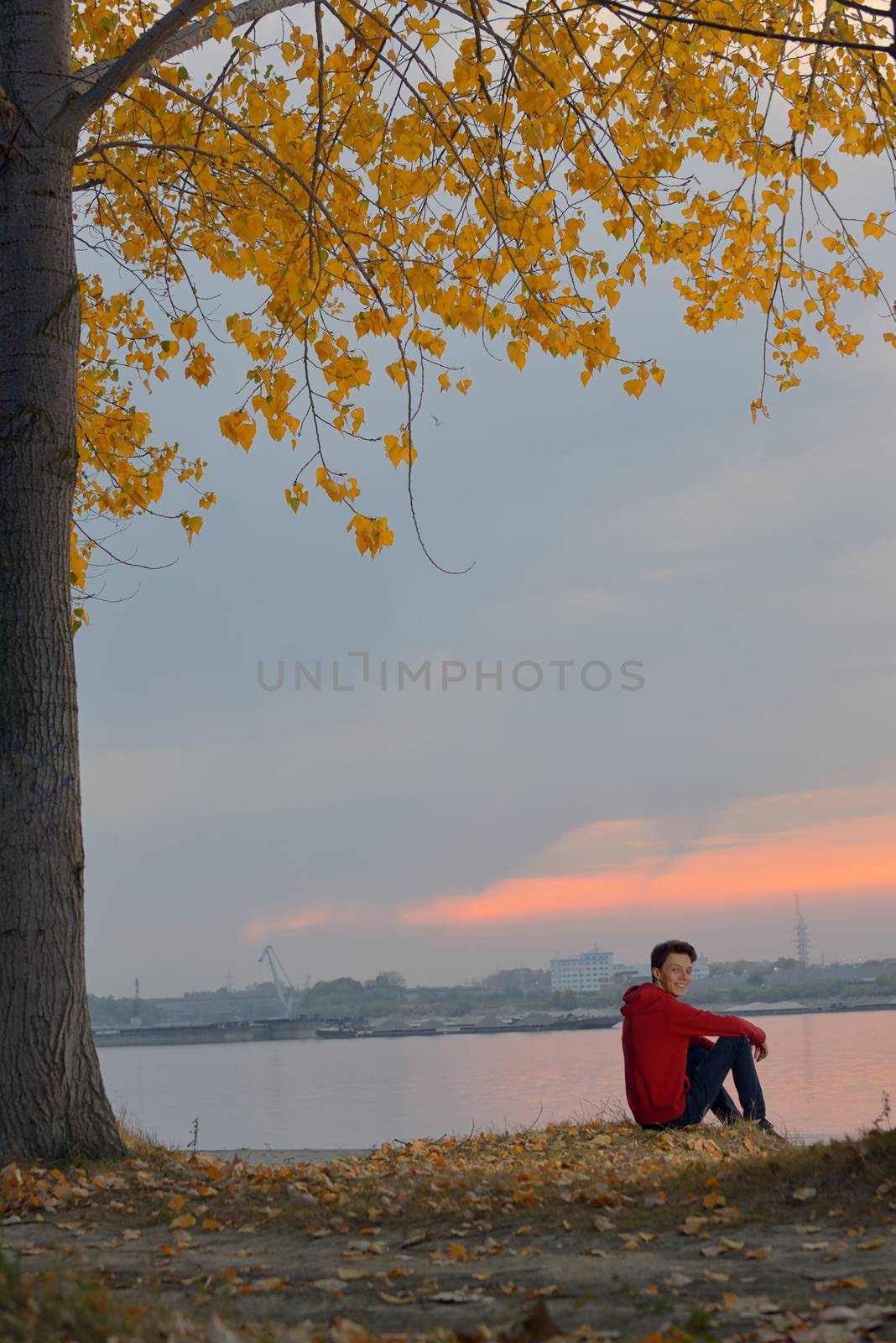 Boy sitting at autumn sunset