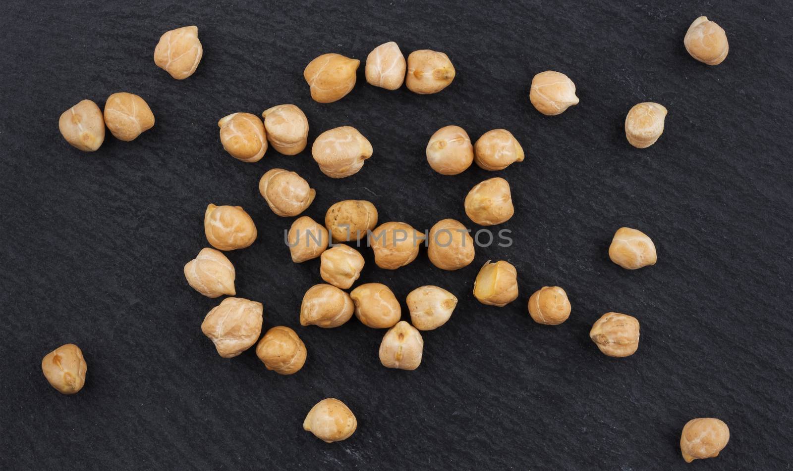 Heap of chickpeas on black background, top view