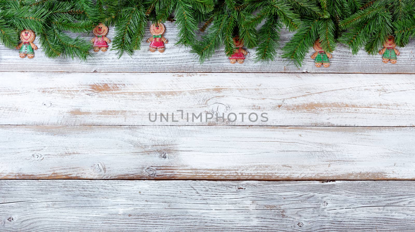 Top border of Christmas evergreen branches and cookie decorations on white vintage wood