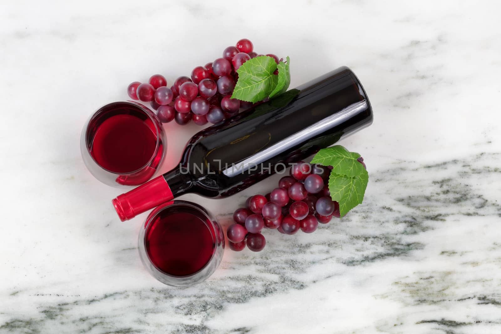 Filled red wine glasses with grapes on marble stone background  by tab1962