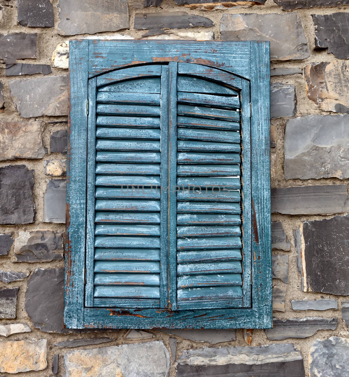 Old wooden window shutters in stone wall 