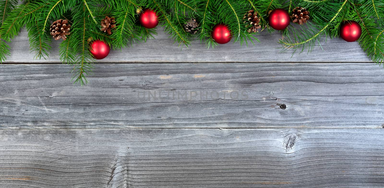 Overhead view of real fir Christmas tree branches and red ornaments on weathered wood  