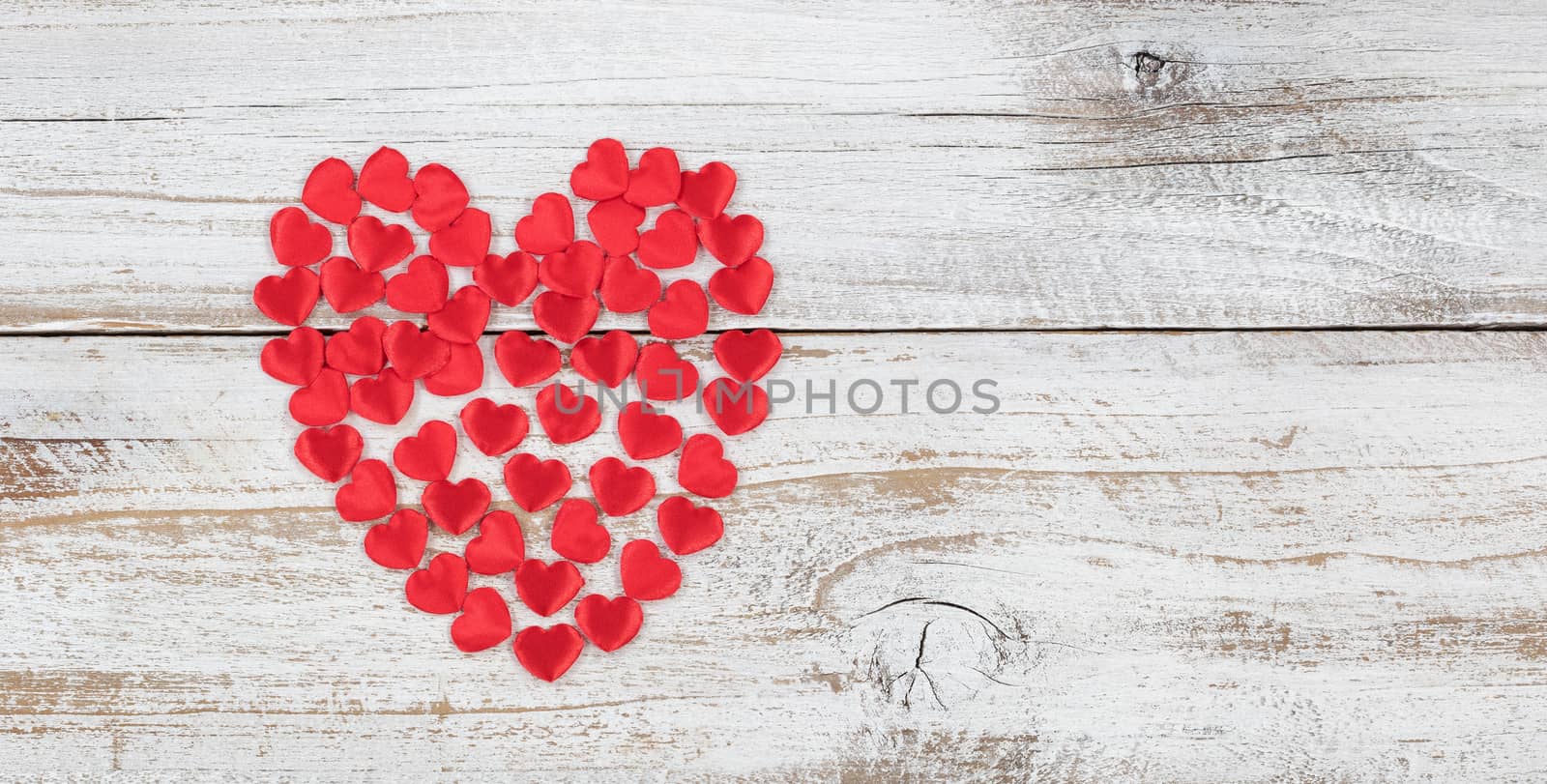 Filled red heart shapes on rustic white wood in flat lay view