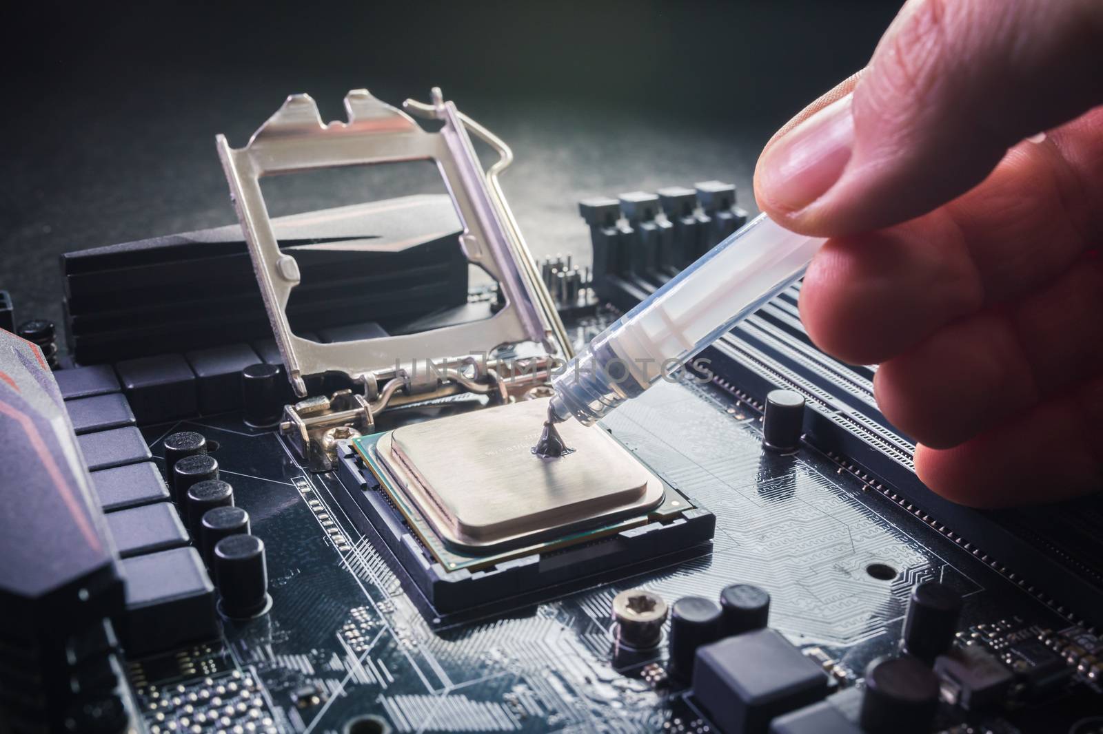 Close up to technician squeezing or application the thermal paste compound on the top of main cpu in the socket. Concept of repairing or upgrading computer hardware. by petrsvoboda91