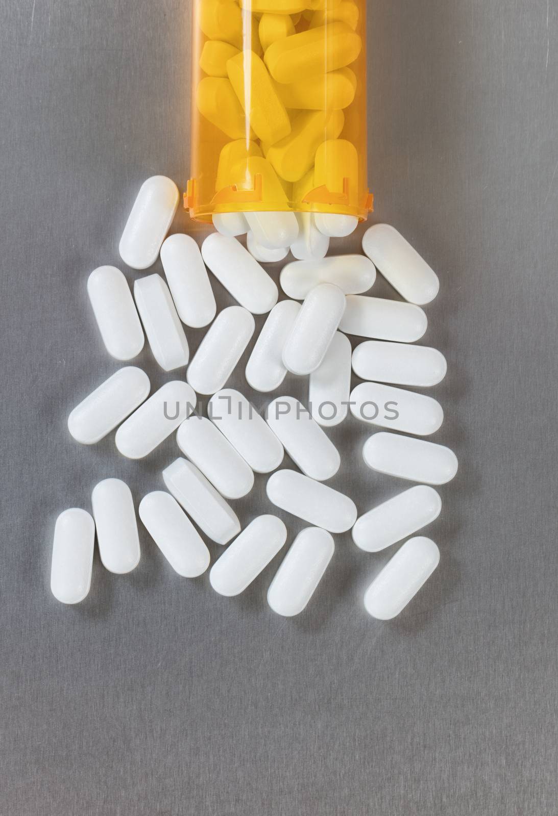 Opioid tablets spilling out of bottle onto stainless steel table by tab1962