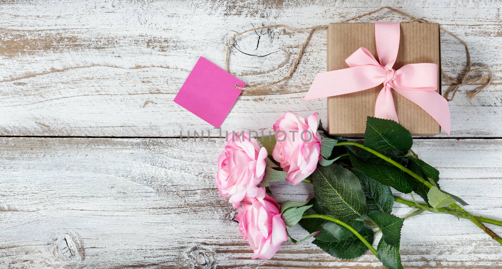Pink roses and gift on rustic white wood  by tab1962