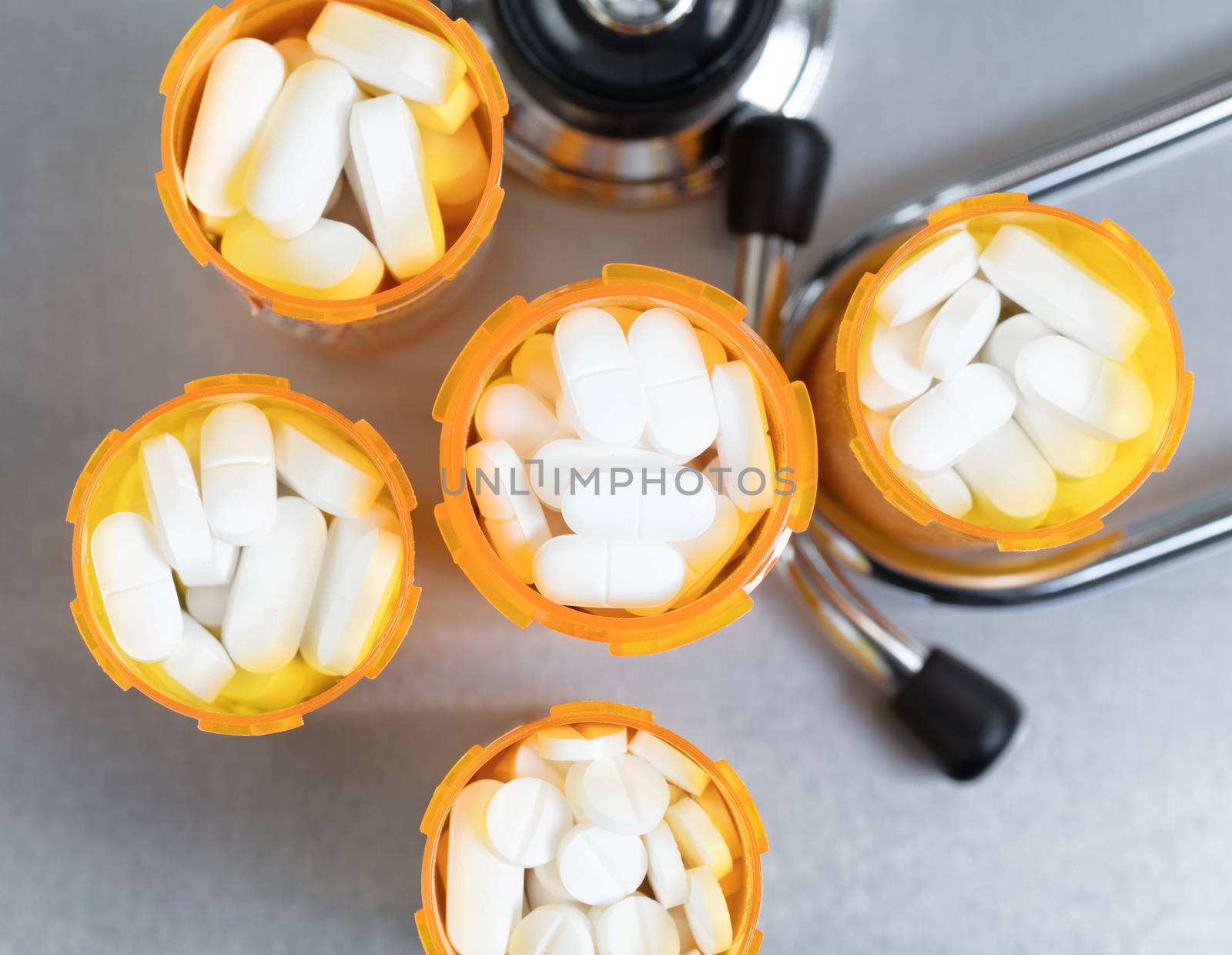 Close up overhead view of full prescription bottles with stethoscope on stainless steel background 