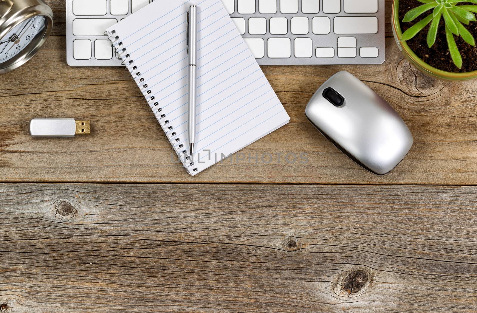 Top part of rustic desktop with work accessories and baby plant. 