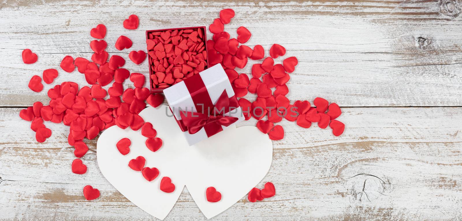 Valentines card and gift box filled with candy heart shapes on rustic white wood in flat lay view