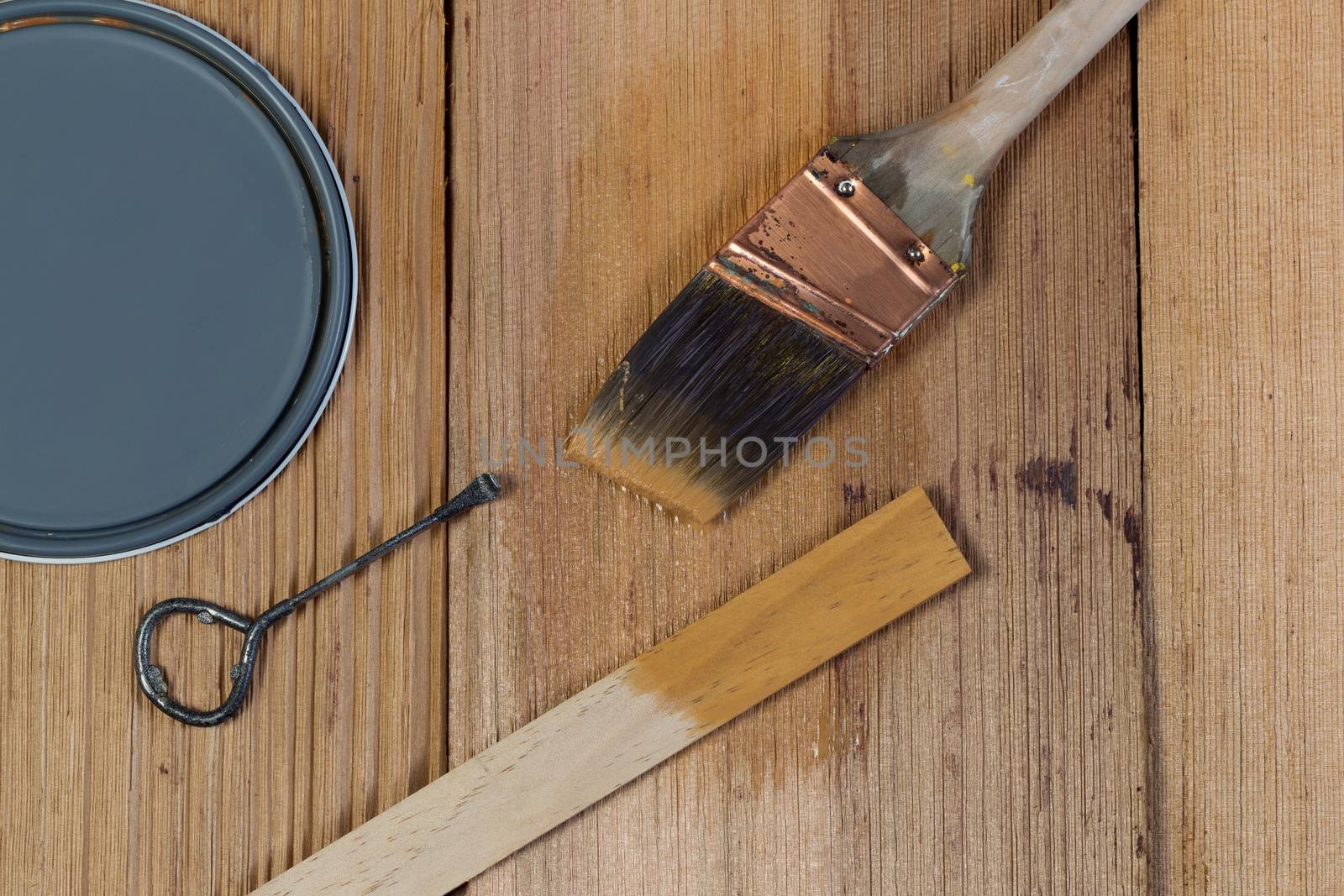 Closeup top view of painting tools consisting of hand brush, stir stick, can opener and paint lid on cedar untreated wooden shingles 