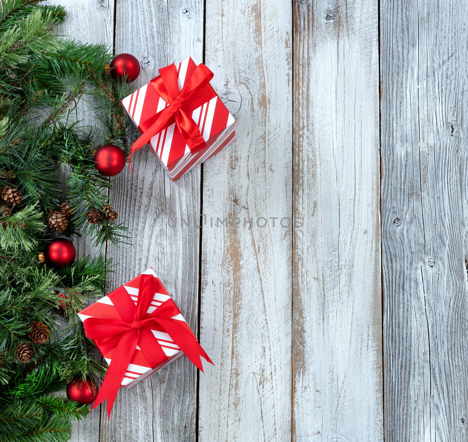 Christmas background with evergreen branches, gifts and red ornaments on white rustic wood 