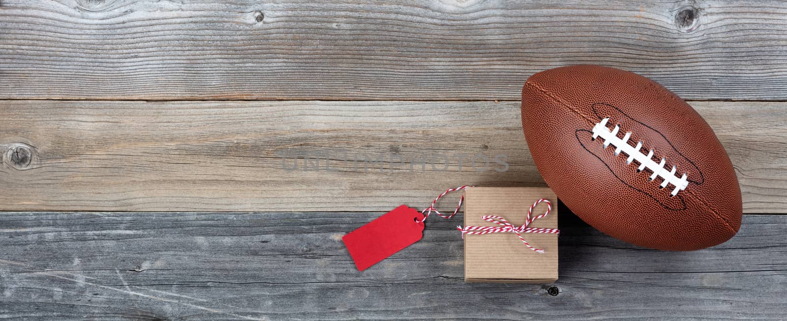Fathers day gift box and single football on rustic wooden plank  by tab1962
