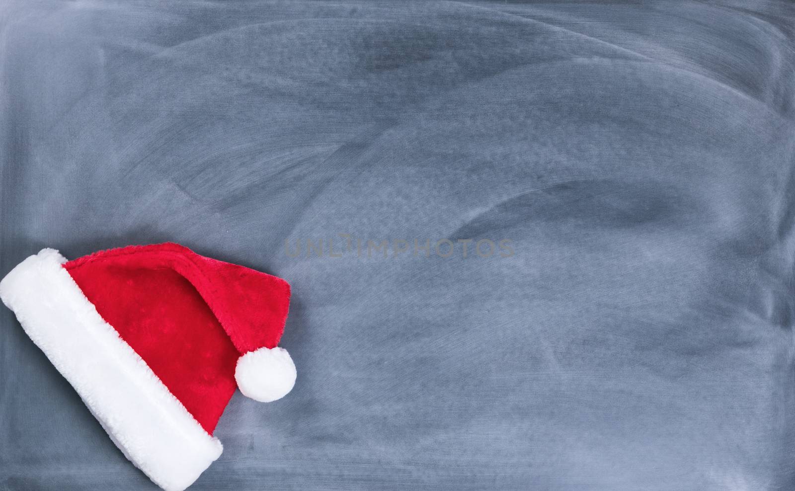 Erased black chalkboard with Santa cap in lower left corner  by tab1962