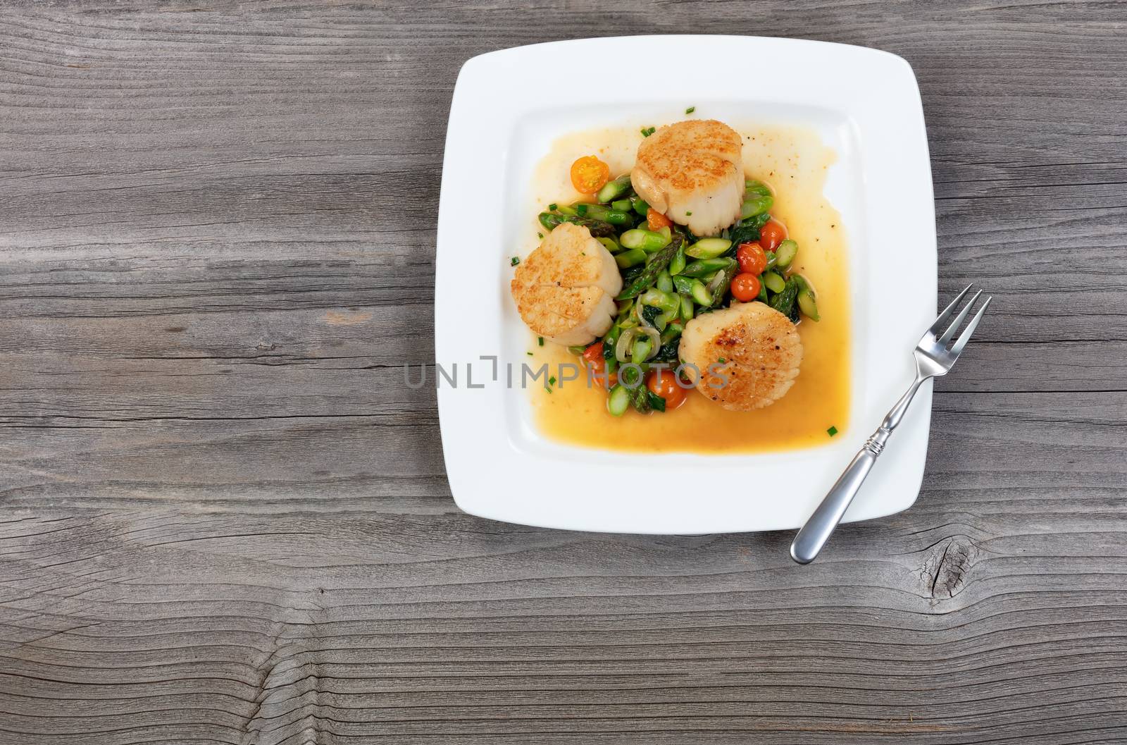 Top view of freshly cooked scallops with vegetables on rustic wooden table 