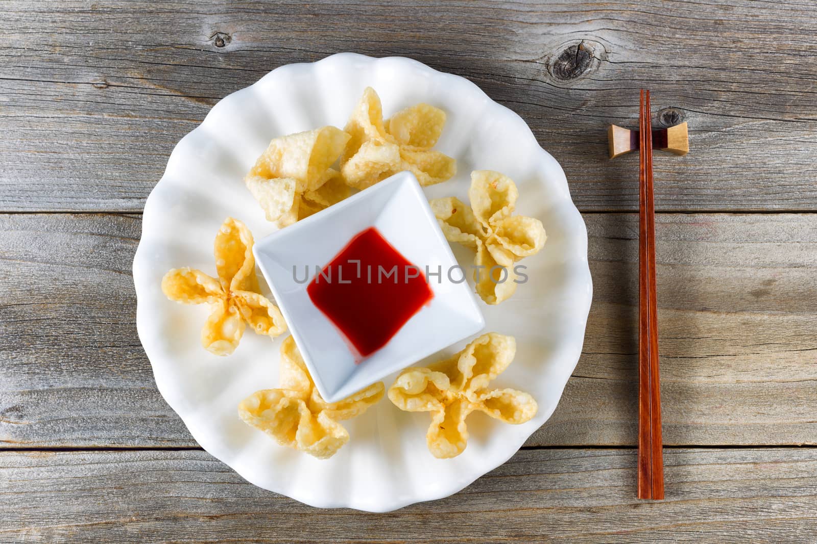 Fried wanton shells and sweet dipping sauce in white bowl on rus by tab1962