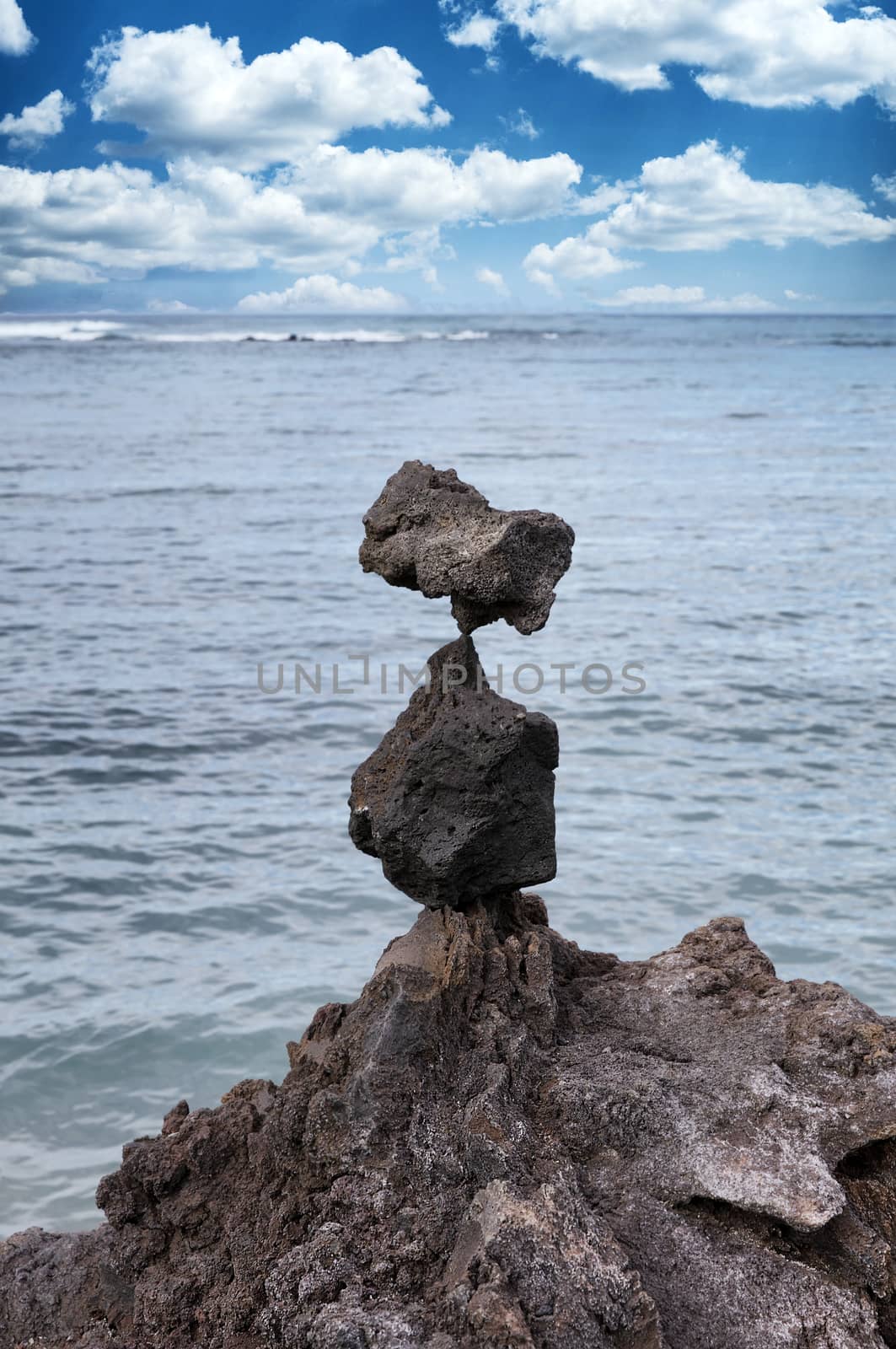 Native rocks stacked vertically with ocean and blue sky  by tab1962