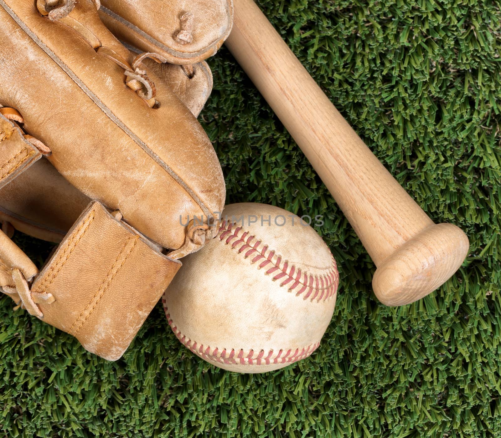 Flat view of old baseball mitt, ball and bat on grass