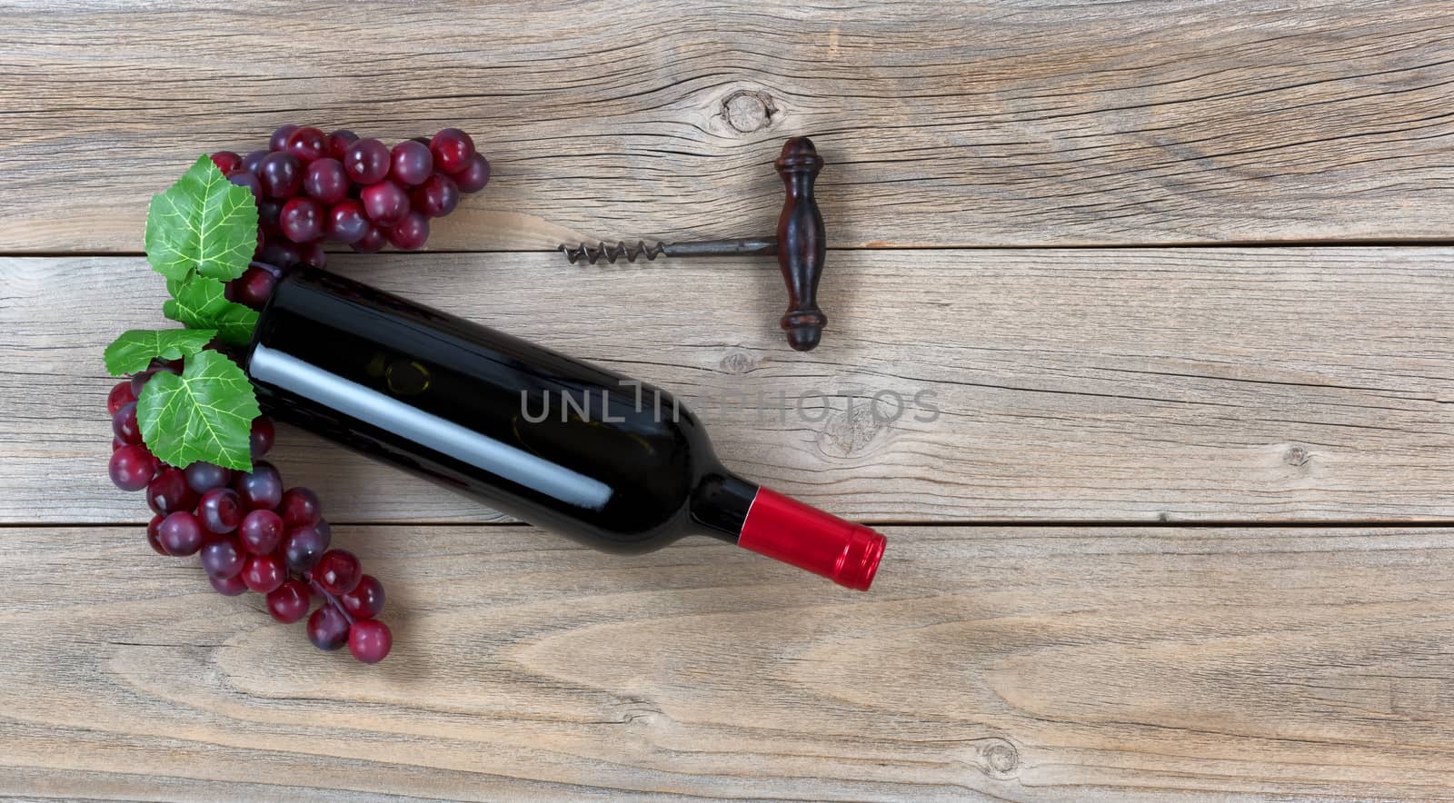 Red wine bottle with grapes and corkscrew on weathered wooden bo by tab1962