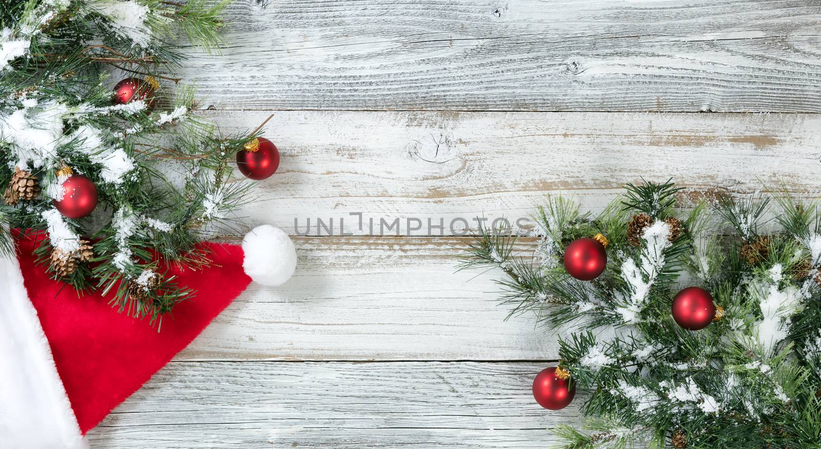 Christmas Rough Fir Tree, Santa hat and snow on Weathered White Wooden Background